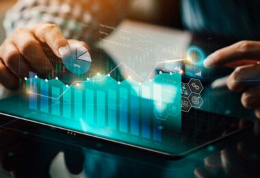 Pessoa utilizando tablet com gráficos digitais, dados e indicadores financeiros representando tecnologia e inteligência artificial no marketing imobiliário.