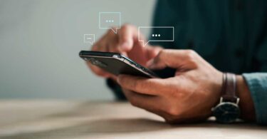 Pessoa manuseando smartphone com balões de conversa digitais, representando atendimento e suporte ao cliente via chatbot com inteligência artificial no mercado imobiliário.