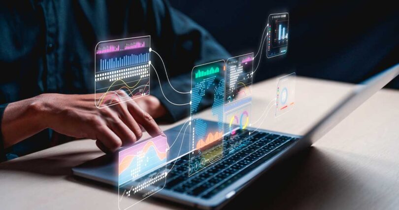 Pessoa usando notebook com gráficos digitais de análise de dados flutuando sobre a tela, simbolizando o uso de inteligência artificial e tecnologia avançada para interpretar informações e tendências no mercado imobiliário.
